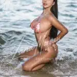 Elite bikini model kneeling in sea