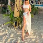 Luxury companion Emma posing with surfboard on tropical beach in Phuket