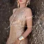 Luxury escort in Phuket posing at the ocean in sparkling golden outfit
