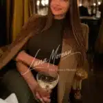 Alena with wine glass, radiant in chic evening style.